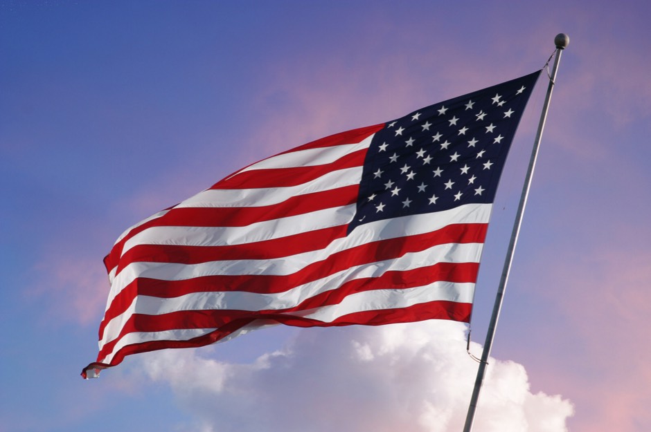 American flag flying in the wind with a lovely sky lighting the background.